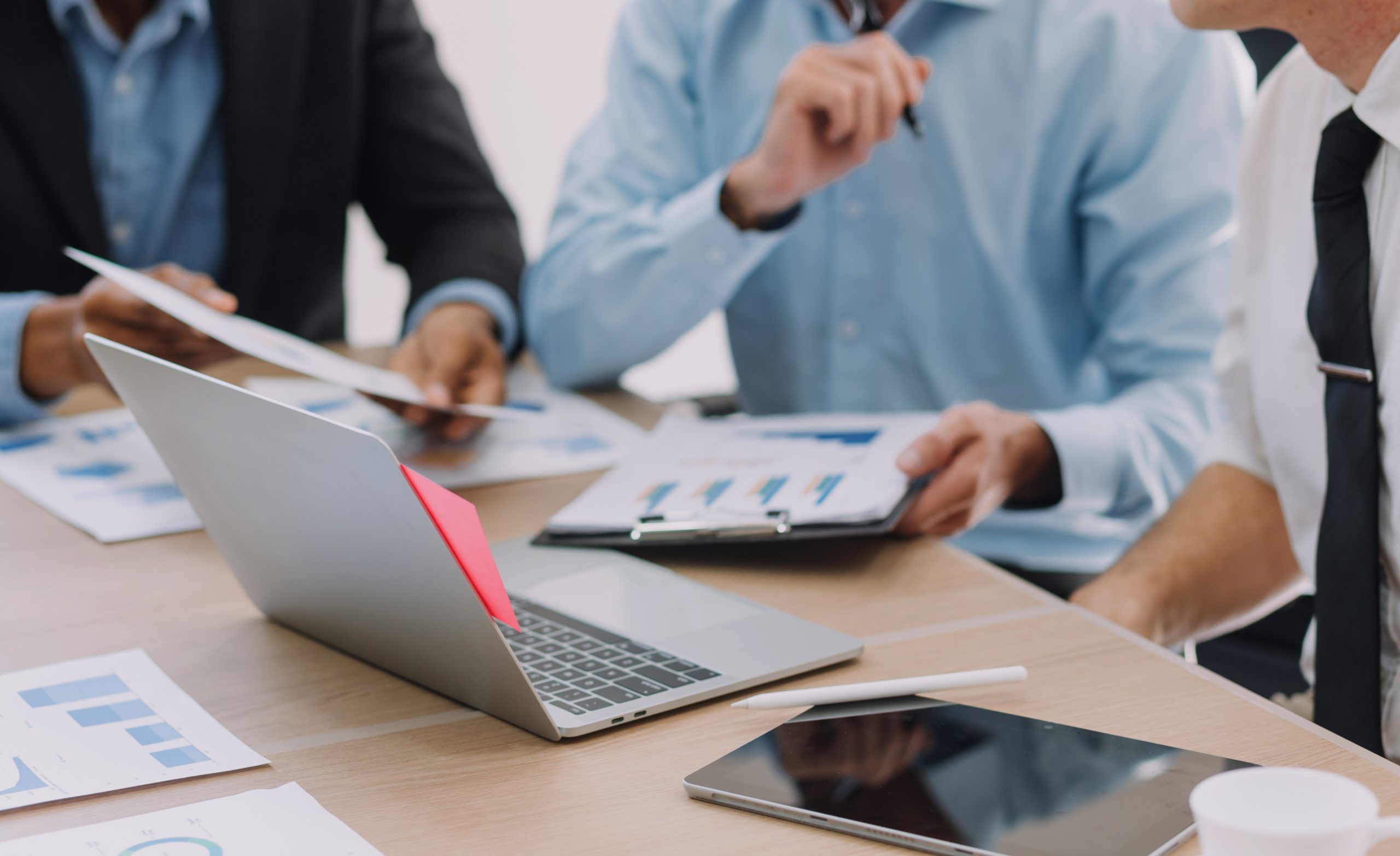 Financial analysts analyze business financial reports on a digital tablet planning investment project during a discussion at a meeting of corporate showing the results of their successful teamwork.